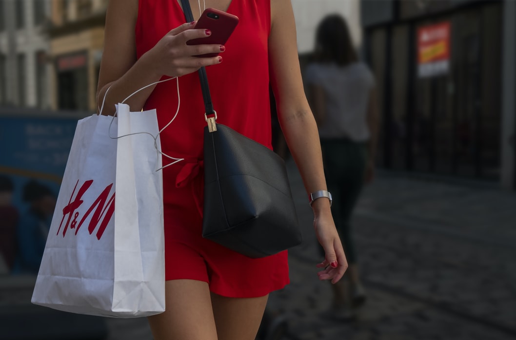 H&Mの紙袋を持った女性が歩いている